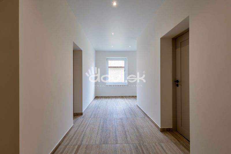 A hallway in a family house with a wooden decor floor and a window at the end.
