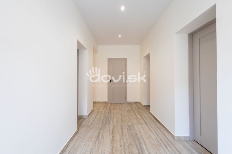 A hallway in a family house with a wooden decor floor and white walls.
