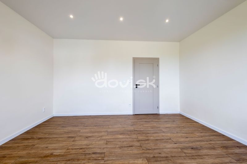 A room with a wooden decor floor and white walls in a family house.
