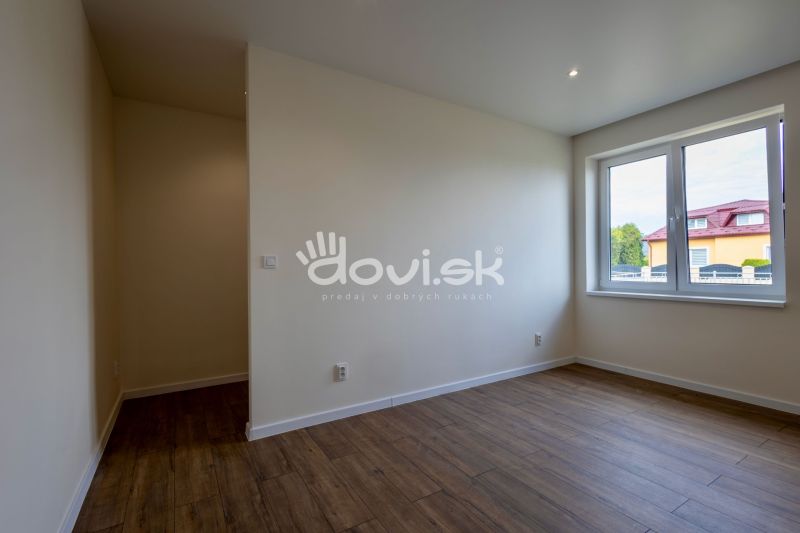 A room in a family house with a wooden decor floor and a large window.