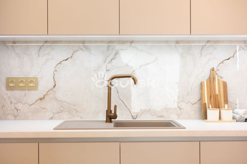 A kitchen unit with a gold faucet and marble tiles in a family house.