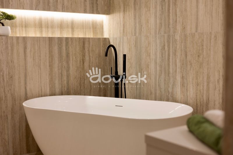 Freestanding bathtub with a modern black faucet in a family house.