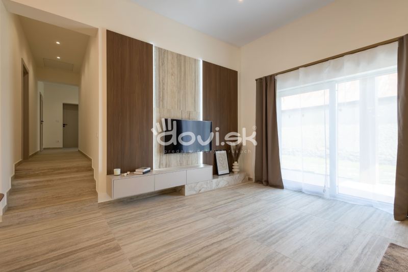 Living room in a family house with a wooden decor floor and a television on the wall.