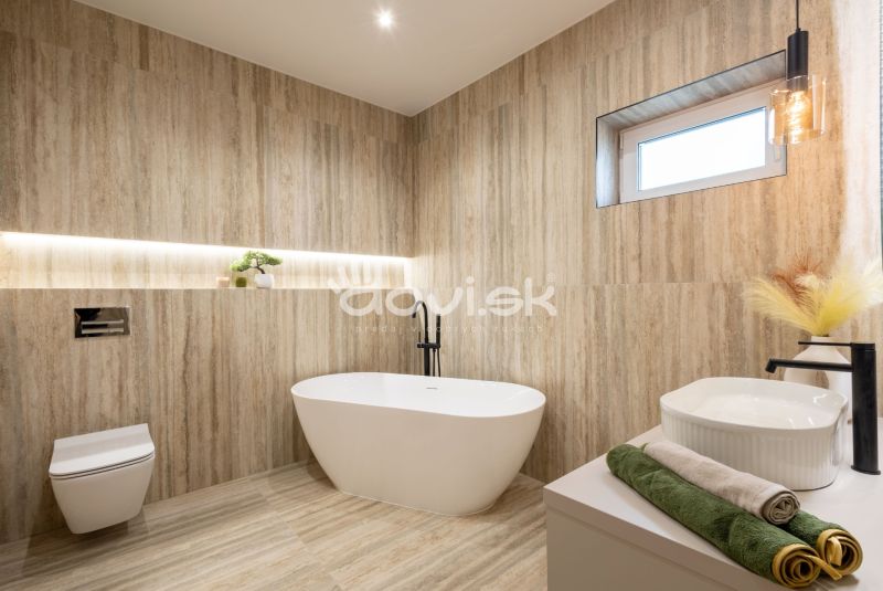 A bathroom in a family house with a wooden decor floor, a bathtub, and decorative lighting.