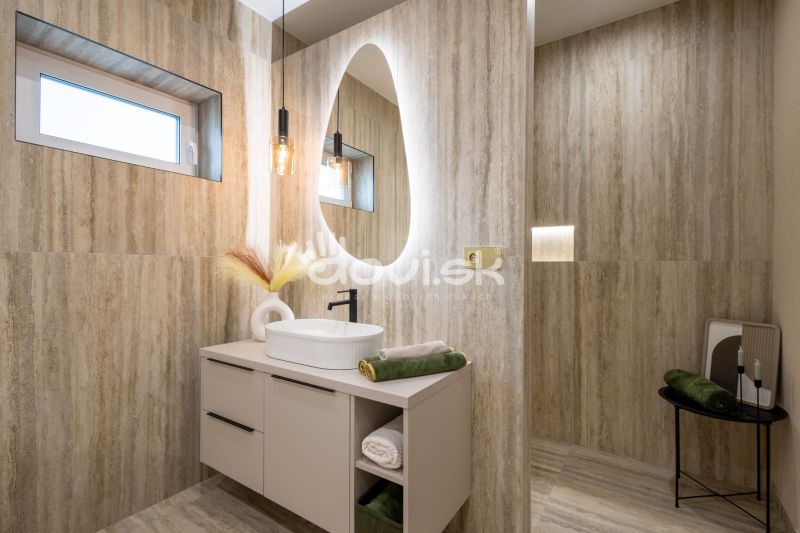 Bathroom with an oval mirror and natural tones, floor with wood decor.