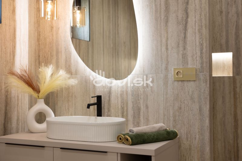 A bathroom in a family house with an oval mirror, a sink, and lights.
