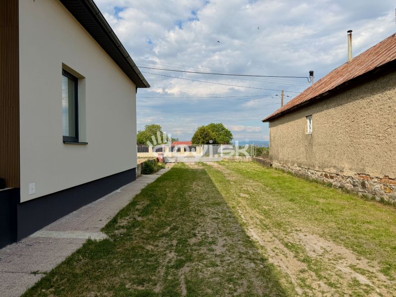A family house in Zemplínska Široká with a lawn between the buildings and a maintained walkway.