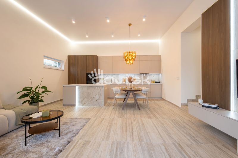 A kitchen and living room in a family house with a decorative light fixture and a wooden decor floor.