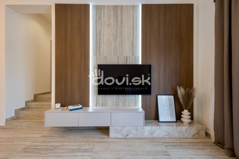 Interior of a family house with a wall featuring wooden decor, a television, and decorations.