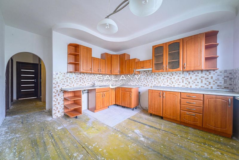 A kitchen with wooden cabinets and tiled backsplash in a 3-room apartment.
