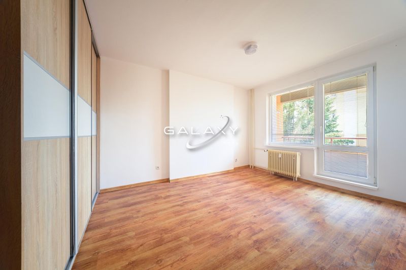 A room in a 3-room apartment with a wooden decor floor and large windows.
