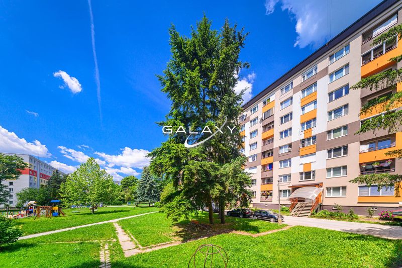 Sídlisko Rimava in Rimavská Sobota with a block of flats, a children's playground, and greenery.