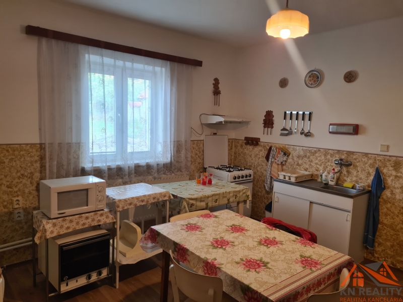 A kitchen in a family house with a microwave, tiles, a table, and a sink.