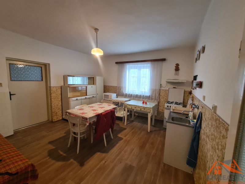 A kitchen in a family house with a wooden decor floor, simple furniture, and a dining table.