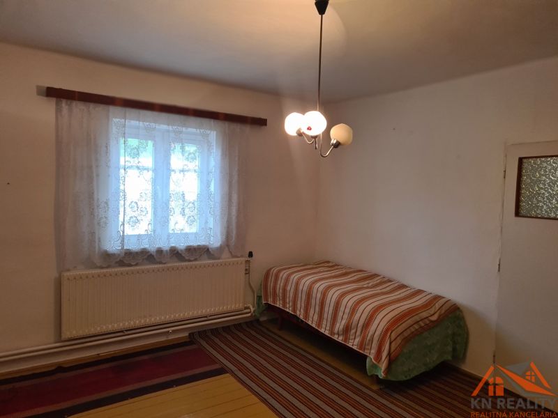 A simple room with a bed and a window, family house, carpet and curtains.