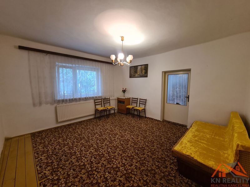 Living room in a family house with a carpet and a yellow sofa.