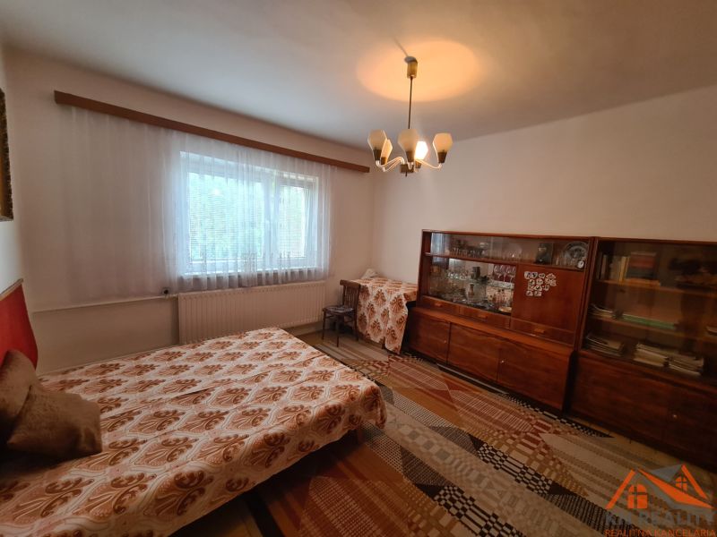 A room with a sofa bed, an older display cabinet, and a curtain, in a family house.