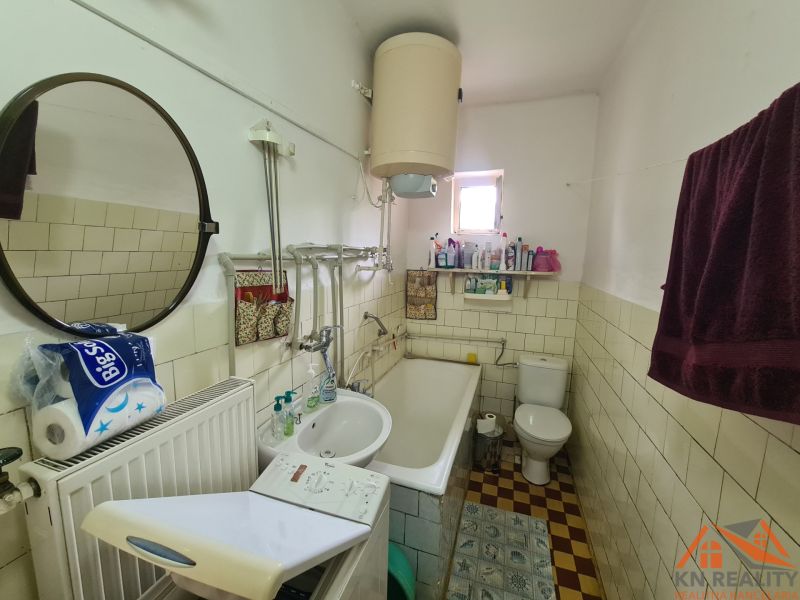 Bathroom with a mirror, sink, bathtub, and washing machine in a family house.