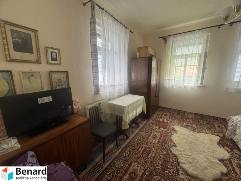A room with a carpet, table, and TV in a family house. Vintage decorations on the walls.