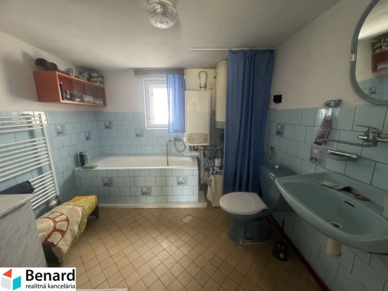 A bathroom in a family house with blue tiles and a bathtub.
