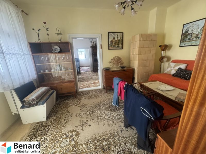 A room in a family house with a sofa set, a display cabinet, and a houseplant.
