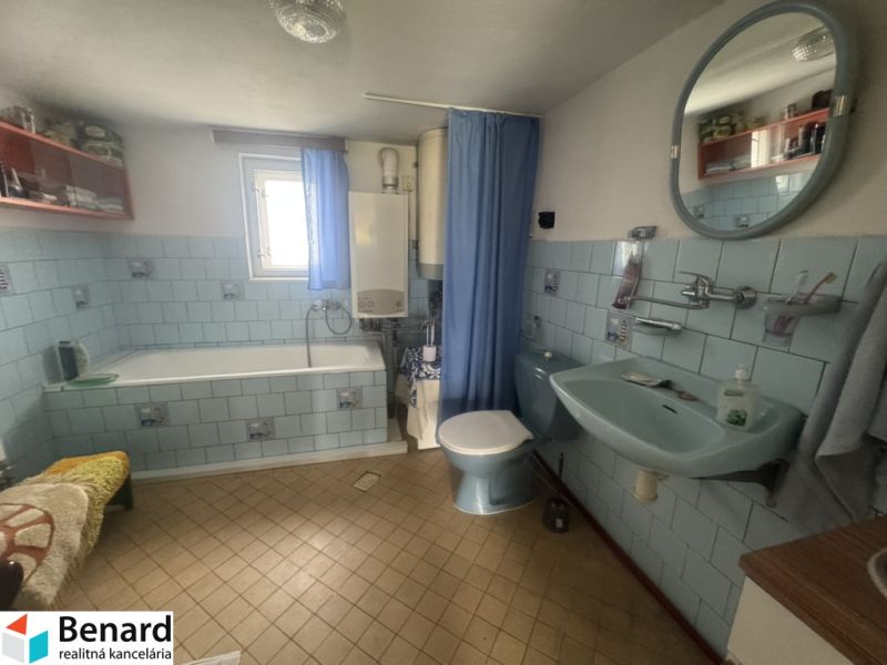 A bathroom in a family house with blue tiles and a bathtub.