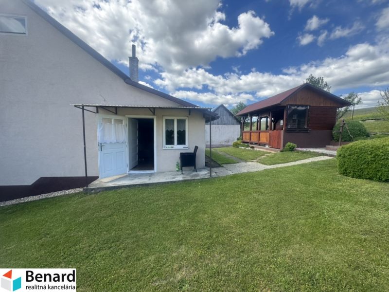 A family house in Orlov with a grassy garden and a gazebo under the blue sky.