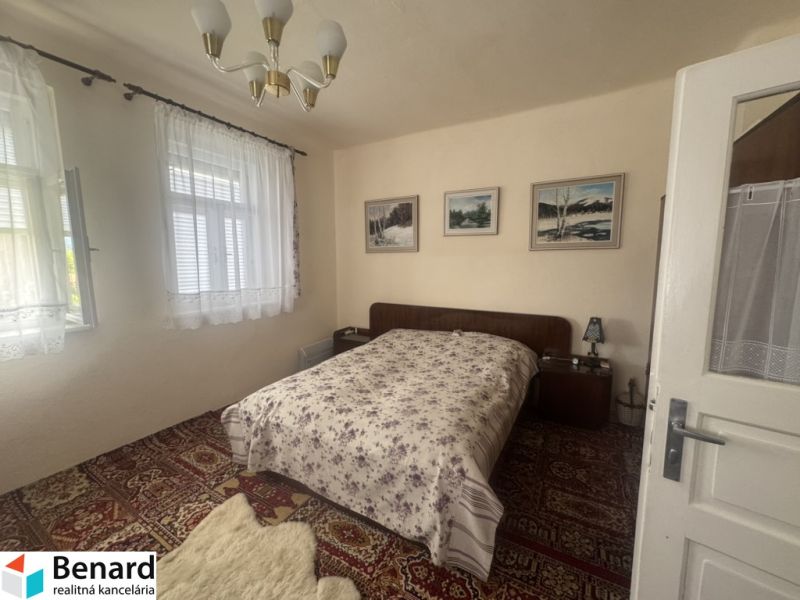 Bedroom in a family house with a bed, carpet, and curtains on the windows.