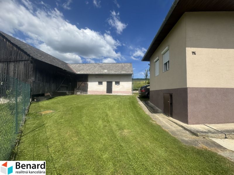 A family house in Orlov with a well-maintained grassy garden and adjacent farm buildings.