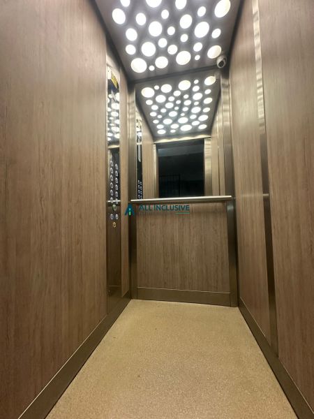 The interior of an elevator in a 2-room apartment with wooden decor on the walls.