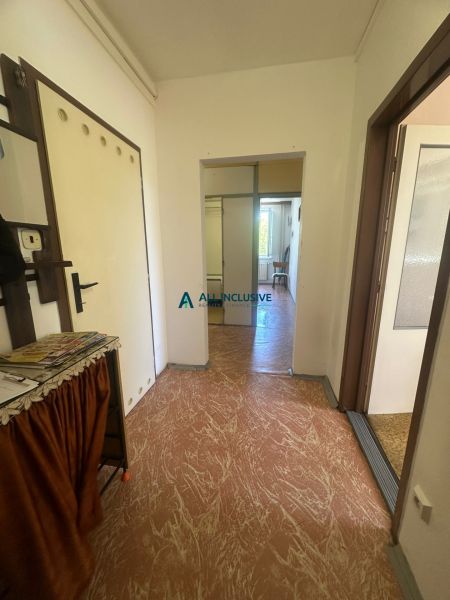 A hallway in a 2-room apartment with simple furnishings and linoleum flooring.