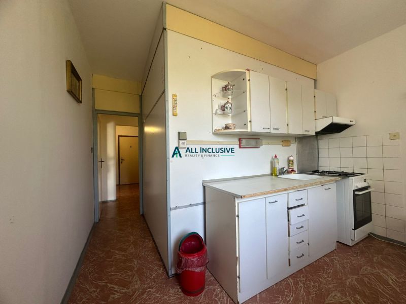 A kitchenette with white cabinets and a stove in a 2-room apartment.