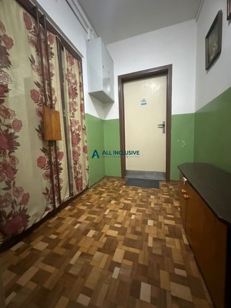 Hallway of a 2-room apartment with a wooden decor floor and floral curtains.