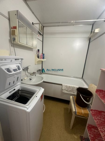 A bathroom with a washing machine and a bathtub in a 2-room apartment with a wooden decor.