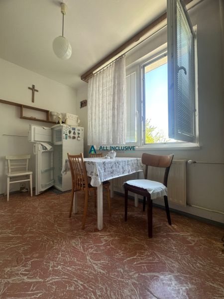 Dining room in a 2-room apartment with a kitchen table, refrigerator, and large window.