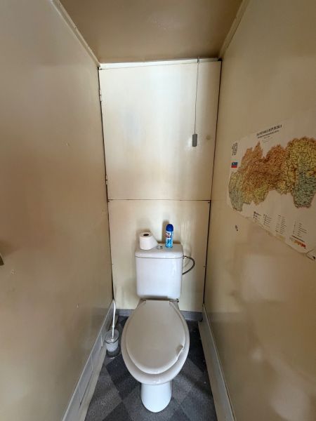 A narrow toilet with a map on the wall in a 3-room apartment.