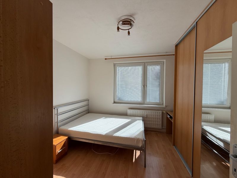 Bedroom in a 3-room apartment with a bed and built-in wardrobe, floor with wooden decor.