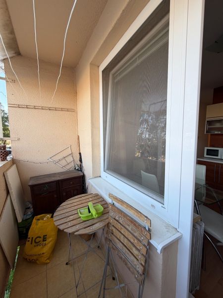 A balcony of a 3-room apartment with a wooden table and chairs, next to the kitchen window.