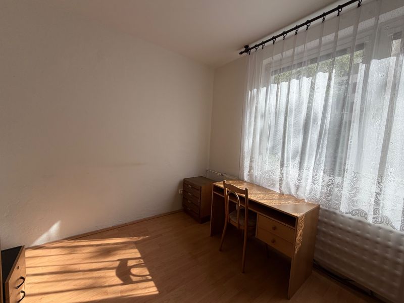 A room with a desk and a chair, a wooden-patterned floor.