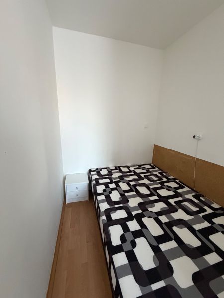 A simple room in a 3-room apartment with a bed and a wooden decor floor.