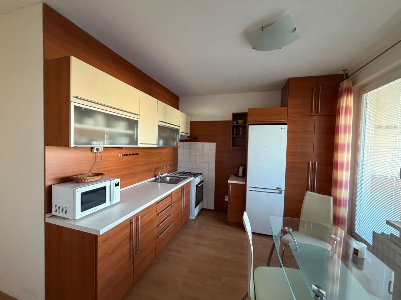A kitchen in a 3-room apartment with white cabinets and a floor with a wood decor.
