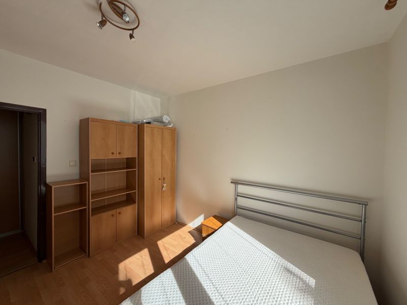 A bedroom in a 3-room apartment with white walls and a floor with a wood decor.