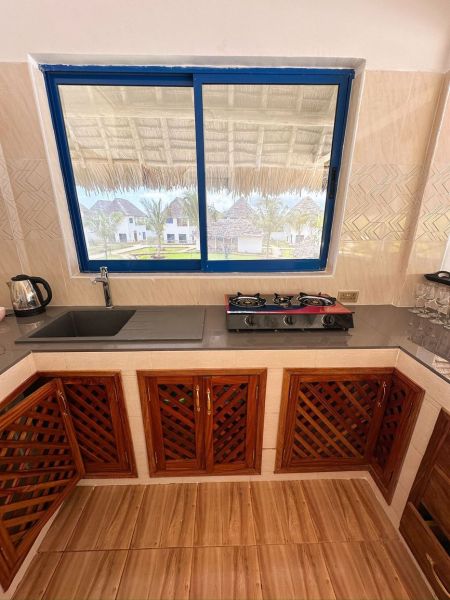 A kitchen in a family house with a gas stove and a view of the grounds.