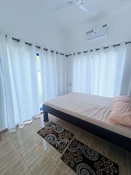 Bedroom in a family house with a bed, curtains, and a wooden decor floor.