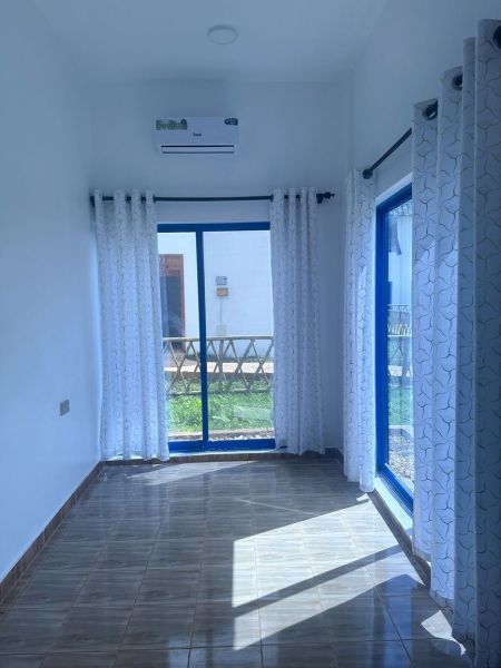 Interior of a family house with a wooden decor floor, large windows, and curtains.