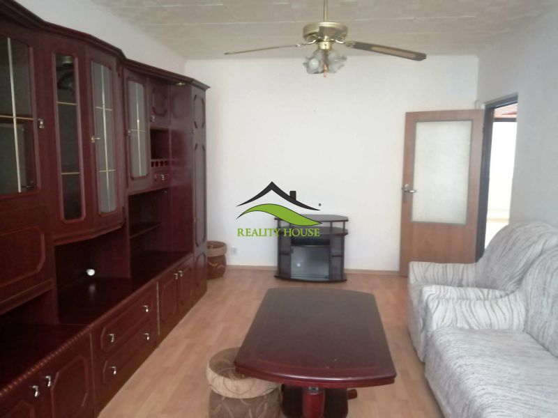 Living room with wood-patterned flooring, a wardrobe, and a sofa in a three-room apartment.