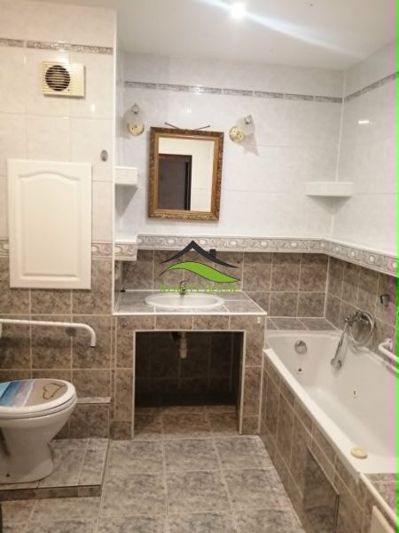 A bathroom in a 3-room apartment with a bathtub, mirror, and toilet, tiled.