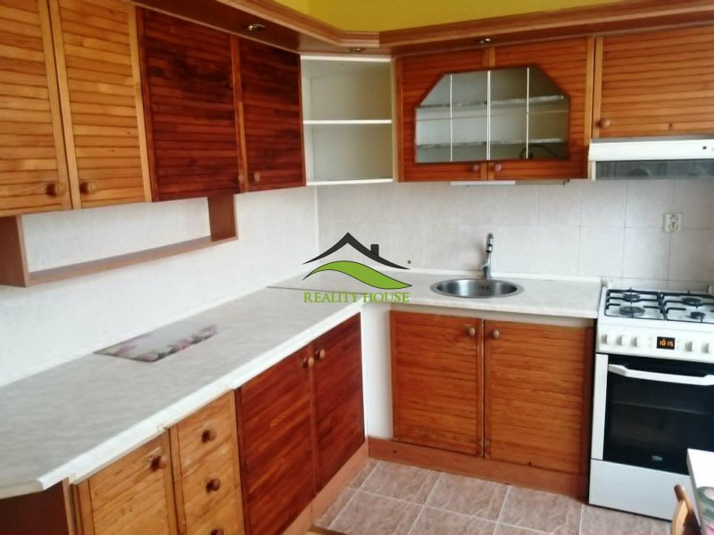 A kitchen in a 3-room apartment with wooden cabinets and a white countertop.