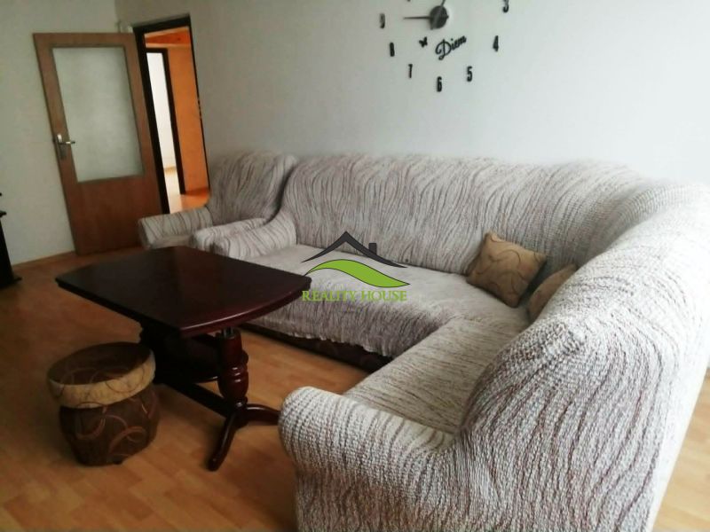 Living room in a three-room apartment with a corner sofa and a wooden decor floor.