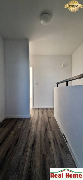 A hallway in a family house with a wooden decor floor and white walls.